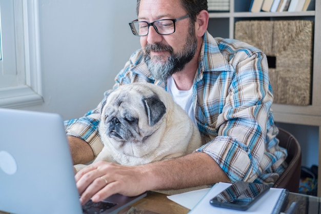 Portrait d'homme mûr et chien travaillant ensemble à l'ordinateur portable avec amour et amitié