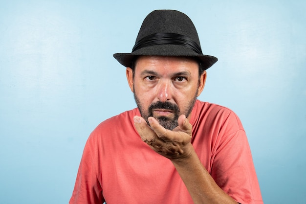 Portrait d'homme mûr debout sur un mur bleu.