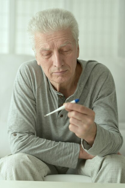 Portrait d'homme mûr malade avec thermomètre