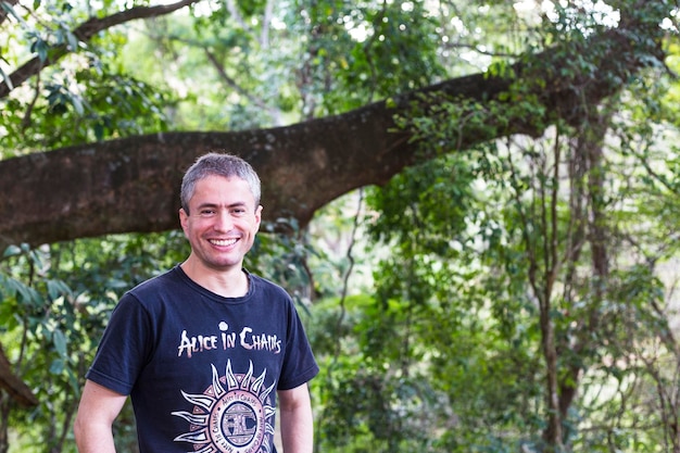 Photo portrait d'un homme mûr souriant debout contre des arbres dans un parc