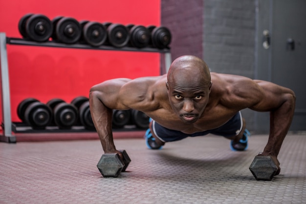 Portrait d&#39;un homme musclé faisant des pompes avec des haltères