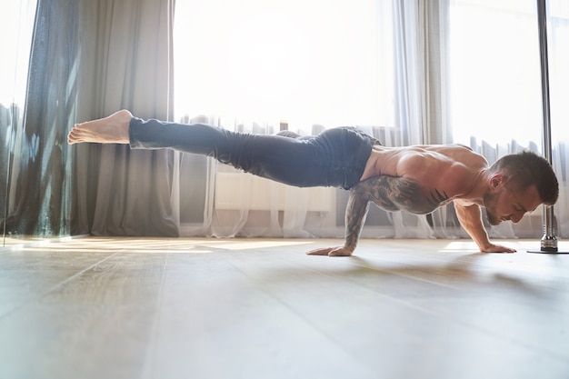 Portrait d'homme musclé poussant sur le plancher en bois dans le club de danse