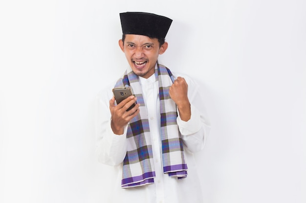 Portrait d'un homme musulman asiatique heureux à l'aide d'un téléphone portable isolé sur fond blanc