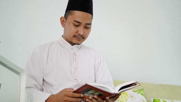 Portrait d'un homme musulman asiatique lisant le saint Coran à la maison