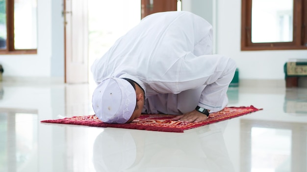 Un portrait d'un homme musulman asiatique prie à la mosquée, le nom de la prière est sholat, mouvement sujud sur sholat