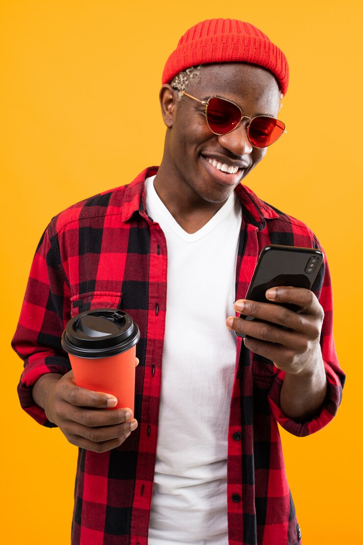 Portrait d'un homme noir américain habillé avec élégance tenant un verre à boire sur la pause-café avec téléphone jaune