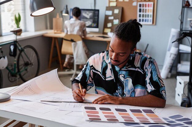 Portrait d'un homme noir créatif travaillant sur des plans d'étage pour l'espace de copie de projet de design d'intérieur