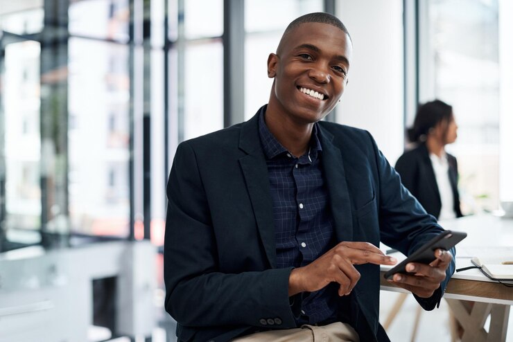 Photo portrait d'homme noir et de négociation avec un téléphone au bureau pour l'investissement ou la finance d'entreprise personne masculine africaine ou homme d'affaires avec un sourire sur un smartphone mobile pour l'investissement financier sur le lieu de travail