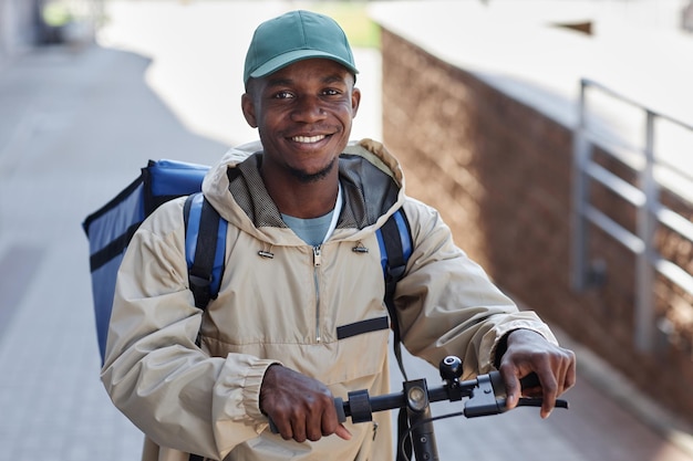 Portrait d'un homme noir souriant en tant que livreur de nourriture en ville