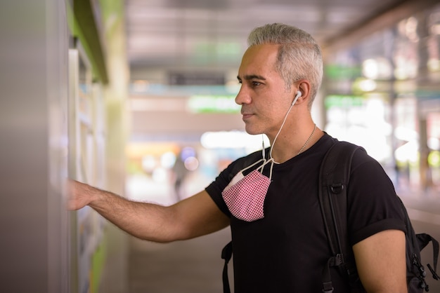 Portrait d'homme persan avec masque pour la protection contre l'épidémie de virus corona et la pollution à la gare du ciel