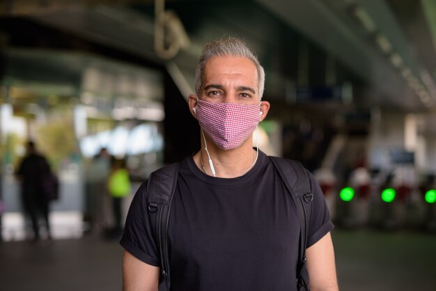 Portrait d'homme persan avec masque pour la protection contre l'épidémie de virus corona et la pollution à la gare du ciel