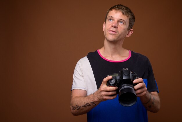 Portrait d'homme photographe à l'aide d'un appareil photo reflex numérique en studio