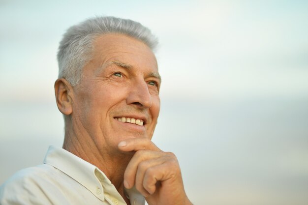 Portrait d'un homme plus âgé attirant sur le fond du ciel