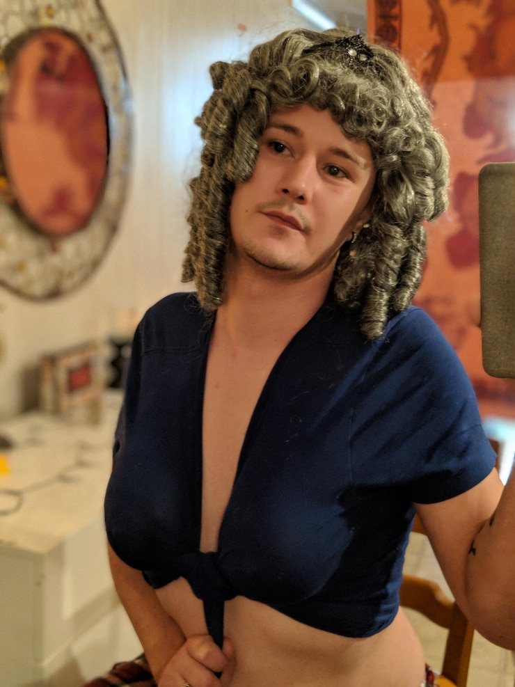 Photo portrait d'un homme portant une perruque et un crop top alors qu'il est assis à la maison