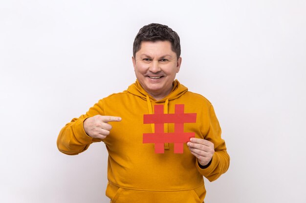 Portrait d'un homme positif optimiste pointant un gros symbole de hachage en papier et souriant à la caméra