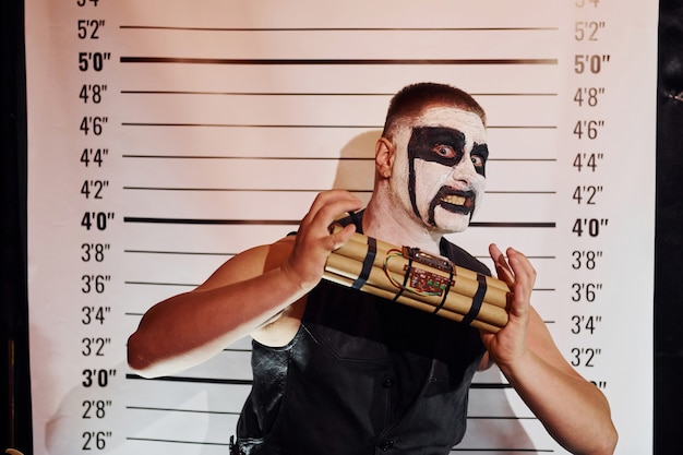 Portrait d'un homme qui participe à la soirée thématique d'halloween en maquillage et costume en métal noir effrayant avec une bombe dans les mains.