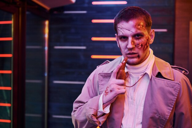 Portrait d'un homme qui participe à la soirée thématique d'halloween en maquillage et costume de zombie.