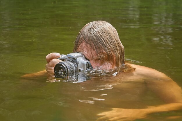 Portrait d'un homme qui photographie en train de nager dans un lac