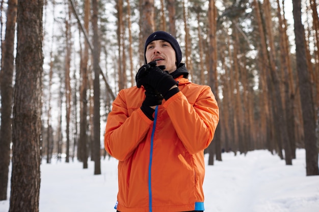 Portrait d'un homme qui s'étend dans le parc sur une belle journée d'hiver enneigée, se préparant à courir