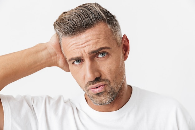 Portrait d'un homme de race blanche des années 30 avec des poils portant un t-shirt décontracté saisissant la tête en raison de la douleur isolée sur blanc