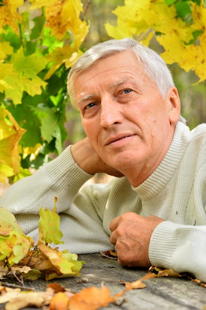 Portrait d'un homme réfléchi mature assis à table à l'extérieur sur fond d'automne