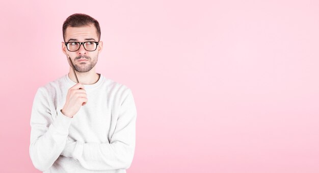 Portrait d'un homme réfléchi tient un crayon et se tournent vers copyspace, sur rose