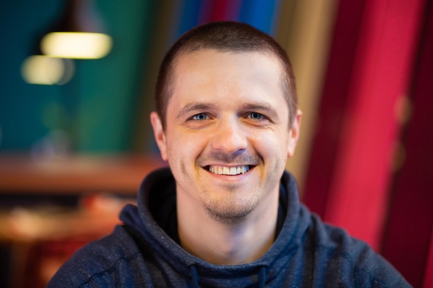 Portrait d'homme regardant à huis clos et souriant. Homme adulte dans la chambre