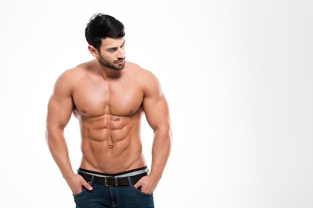 Portrait d'un homme de remise en forme avec torse nu debout isolé sur un mur blanc