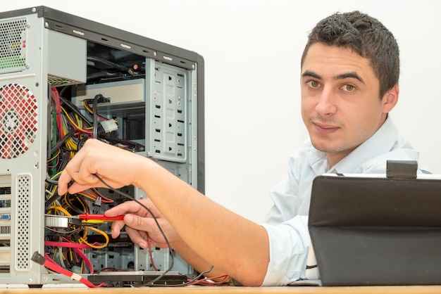 Photo portrait d'un homme réparant un processeur sur une table sur un fond blanc