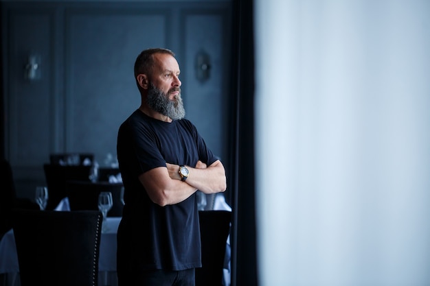 Portrait d'un homme réussi adulte aux cheveux gris avec un visage sérieux dans un t-shirt noir