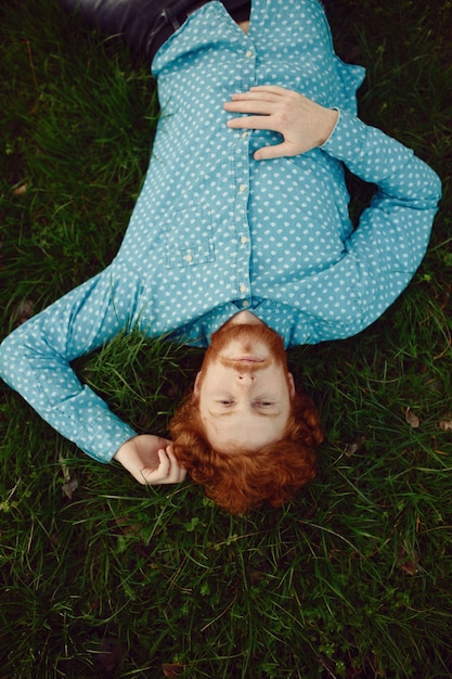 Portrait homme rougeâtre frisé couché sur l'herbe verte