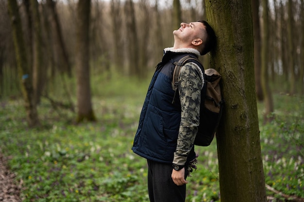 Portrait d'homme avec sac à dos appuyé contre un arbre sur la forêt Amour de la nature