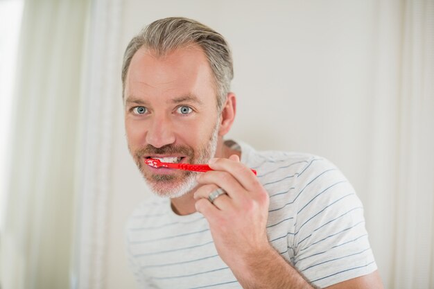 Portrait d'homme se brosser les dents dans la salle de bain