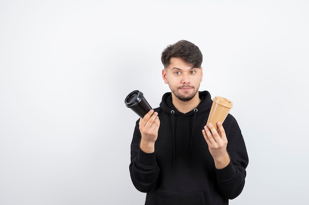 Portrait d'homme séduisant tenant deux tasses à emporter