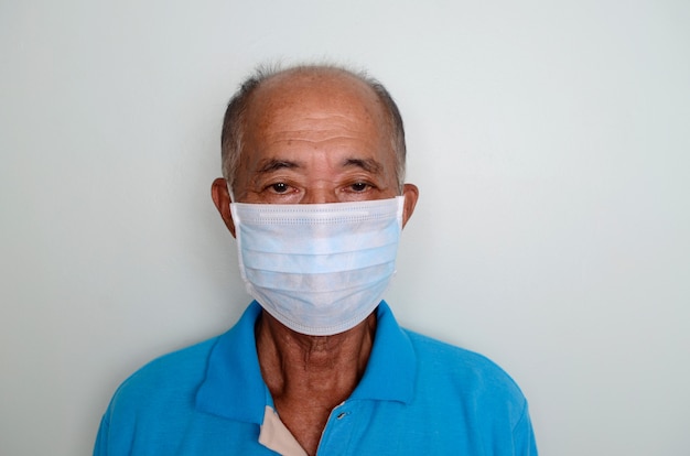 Photo portrait d'un homme senior asiatique, 60 ans portant un masque médical. un concept du danger du coronavirus pour les personnes âgées.