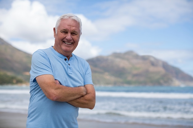 Portrait d'un homme senior debout avec les bras croisés sur la plage