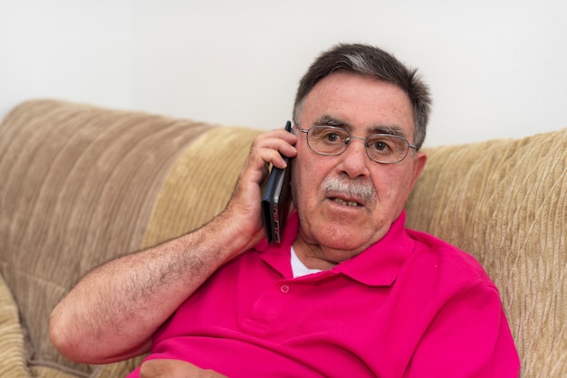 Portrait d&#39;un homme senior expression sérieuse parlant au téléphone