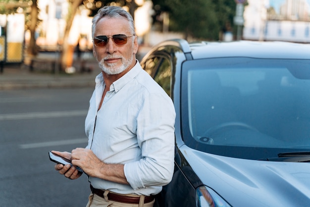 Portrait d'homme senior à l'extérieur. Homme d'âge moyen debout près de sa voiture SUV