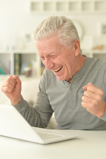 Portrait d'un homme senior heureux à l'aide d'un ordinateur portable