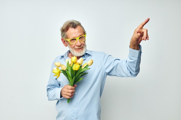 Portrait d'un homme senior heureux dans une chemise bleue avec un bouquet de fleurs fond clair