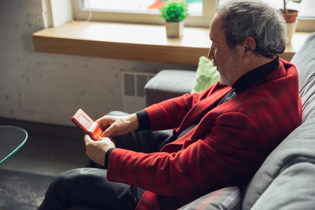 Portrait d'un homme senior millénaire avec des jouets rétro rencontrant des choses du passé et s'amusant