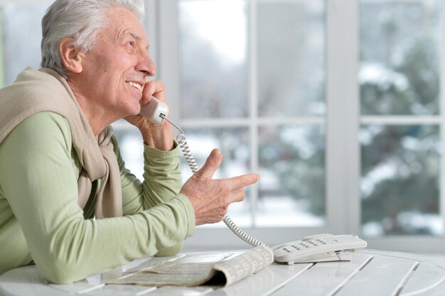 Portrait d'homme senior avec téléphone à la maison