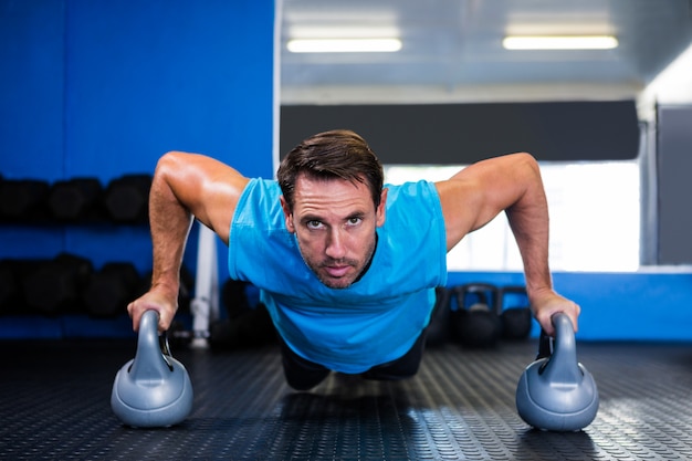 Portrait d'un homme sérieux faisant des pompes avec kettlebell