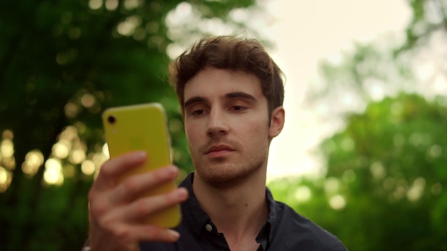 Portrait d'un homme sérieux lisant un message sur un téléphone portable lors d'une promenade dans le parc