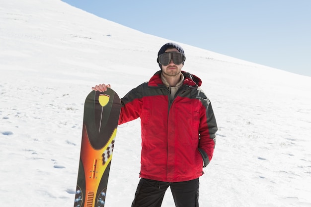 Portrait d&#39;un homme sérieux avec planche de ski debout sur la neige