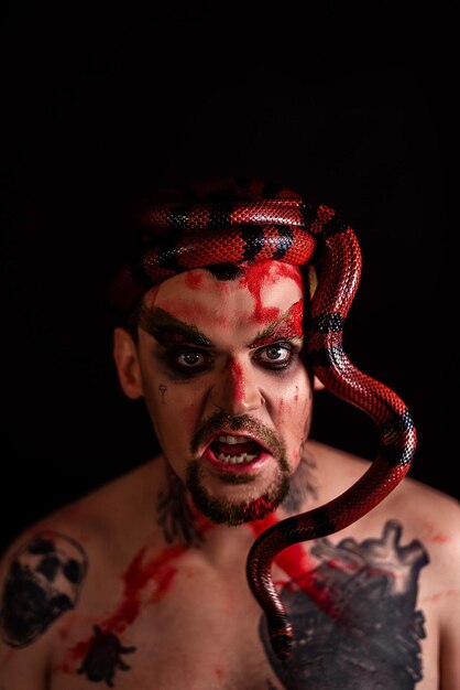 Photo portrait d'un homme avec un serpent sur un fond noir