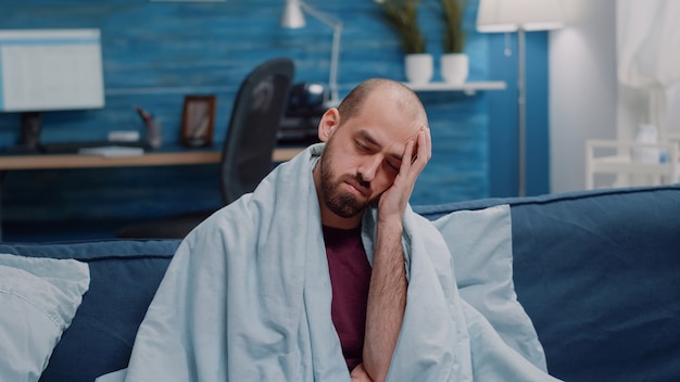 Portrait d'un homme souffrant de maux de tête regardant la caméra