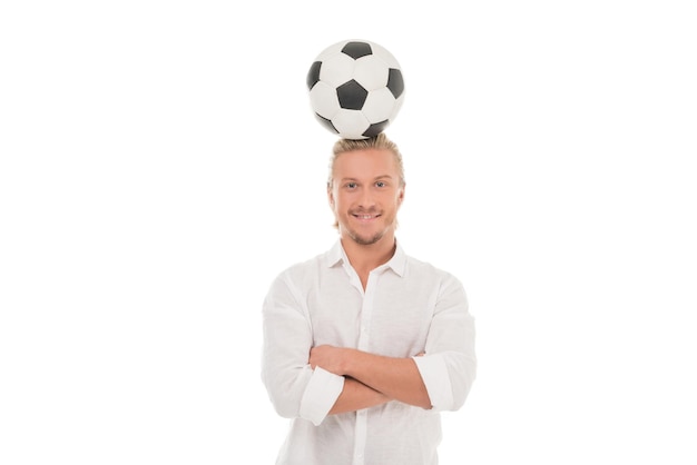 Portrait d'un homme souriant avec un ballon de football sur la tête regardant la caméra isolée sur blanc