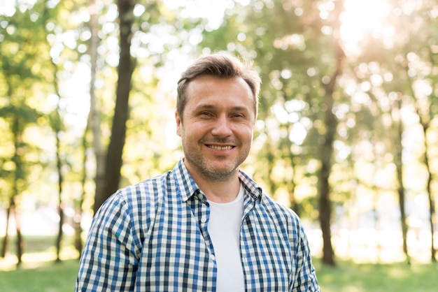 Photo portrait d'un homme souriant, debout dans le parc