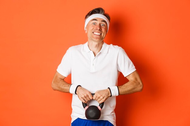 Portrait d'un homme souriant debout sur un fond orange